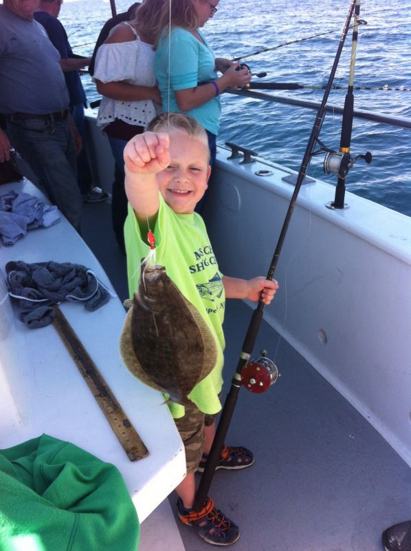 little boy holding flounder still hooked on fishing line