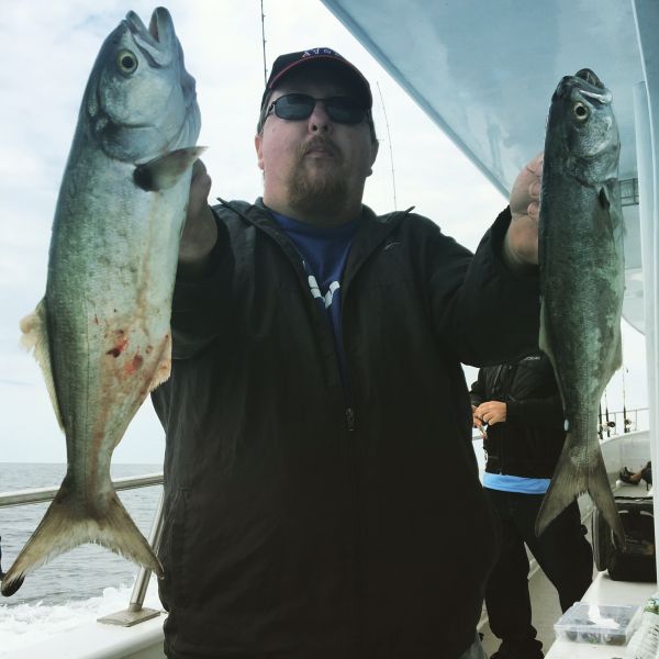 man holding 2 fish he caught