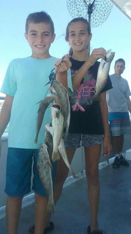 2 kids holding a handful of fish they caught