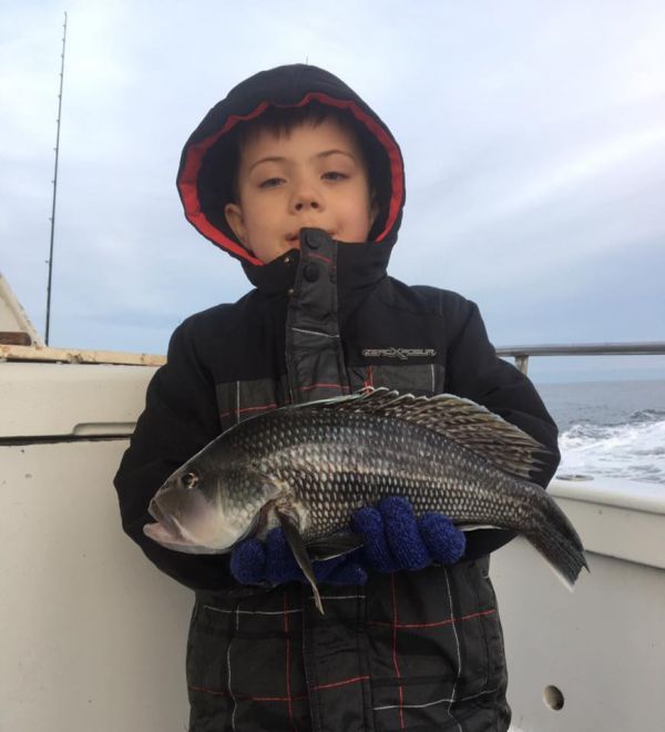 small child in winter jacket holding a recently caught fish