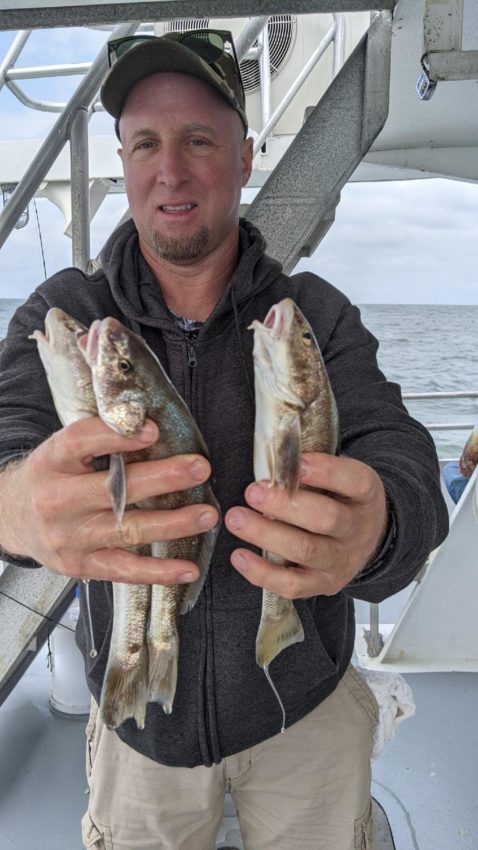 Man holding three fish on boat